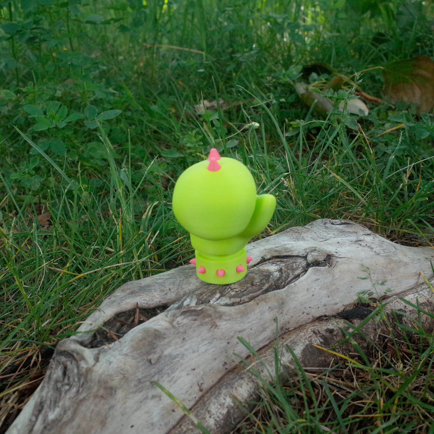 Front view of a neon green spiked glove toy placed on a tree stump in the grass