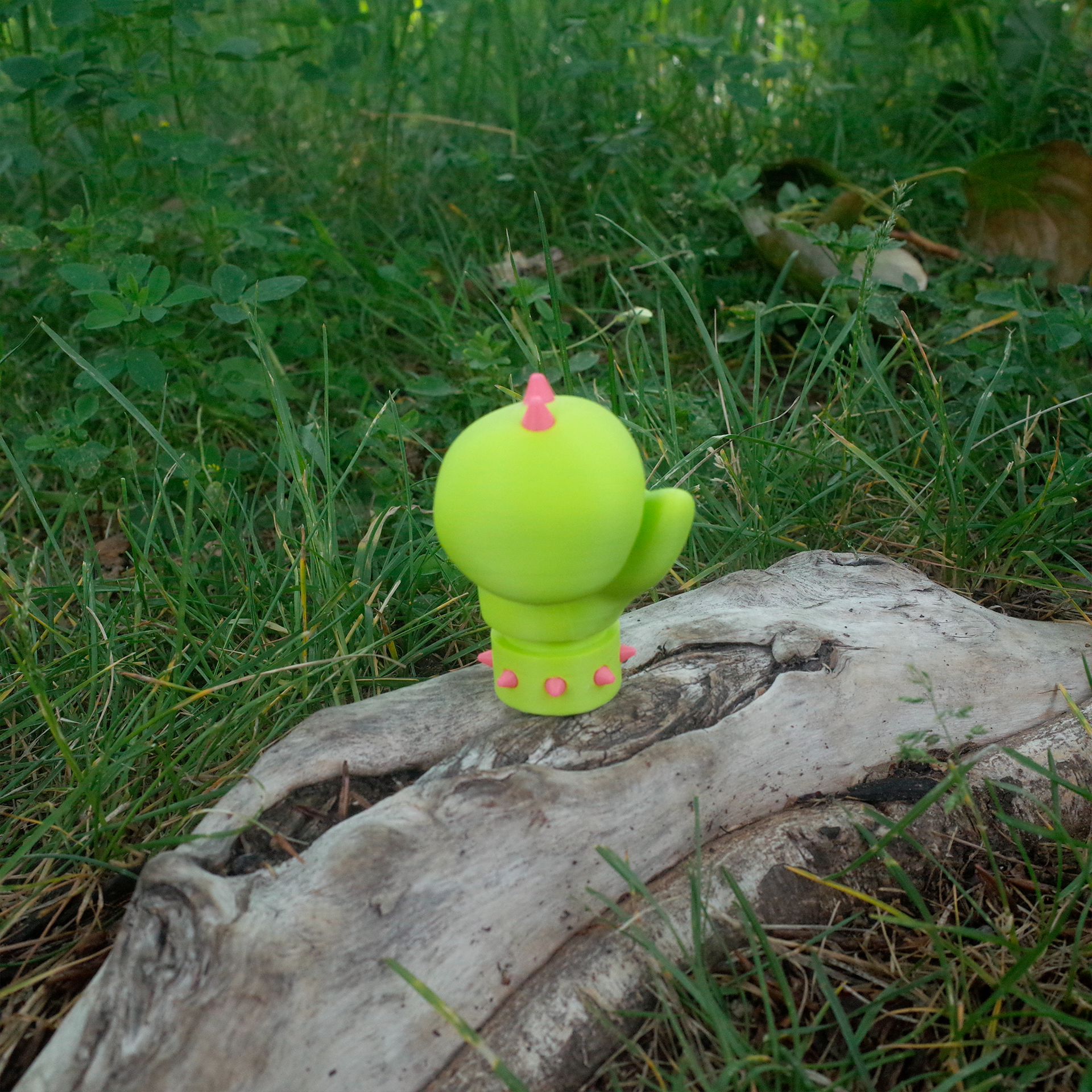 Front view of a neon green spiked glove toy placed on a tree stump in the grass