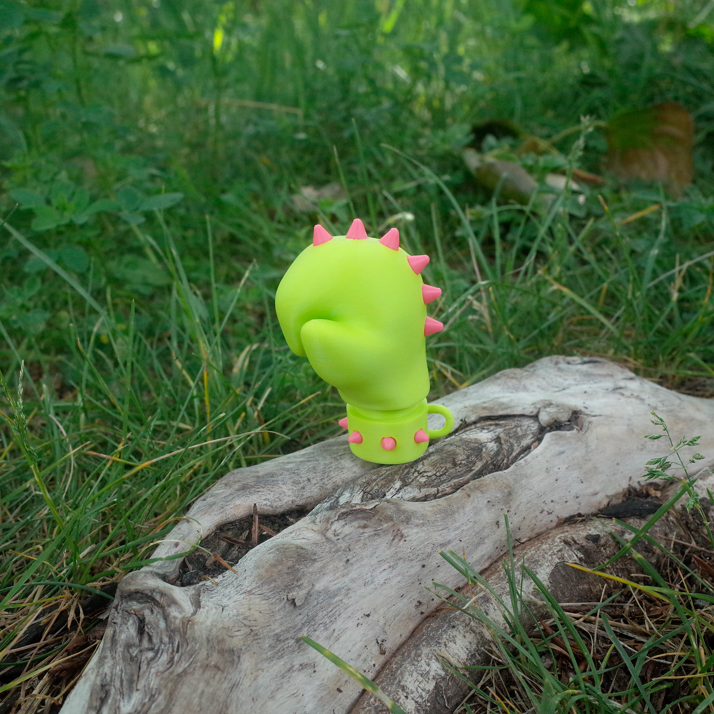 Side view of Neon Jab 3D printed glove toy standing upright on natural wood with pink spikes visible