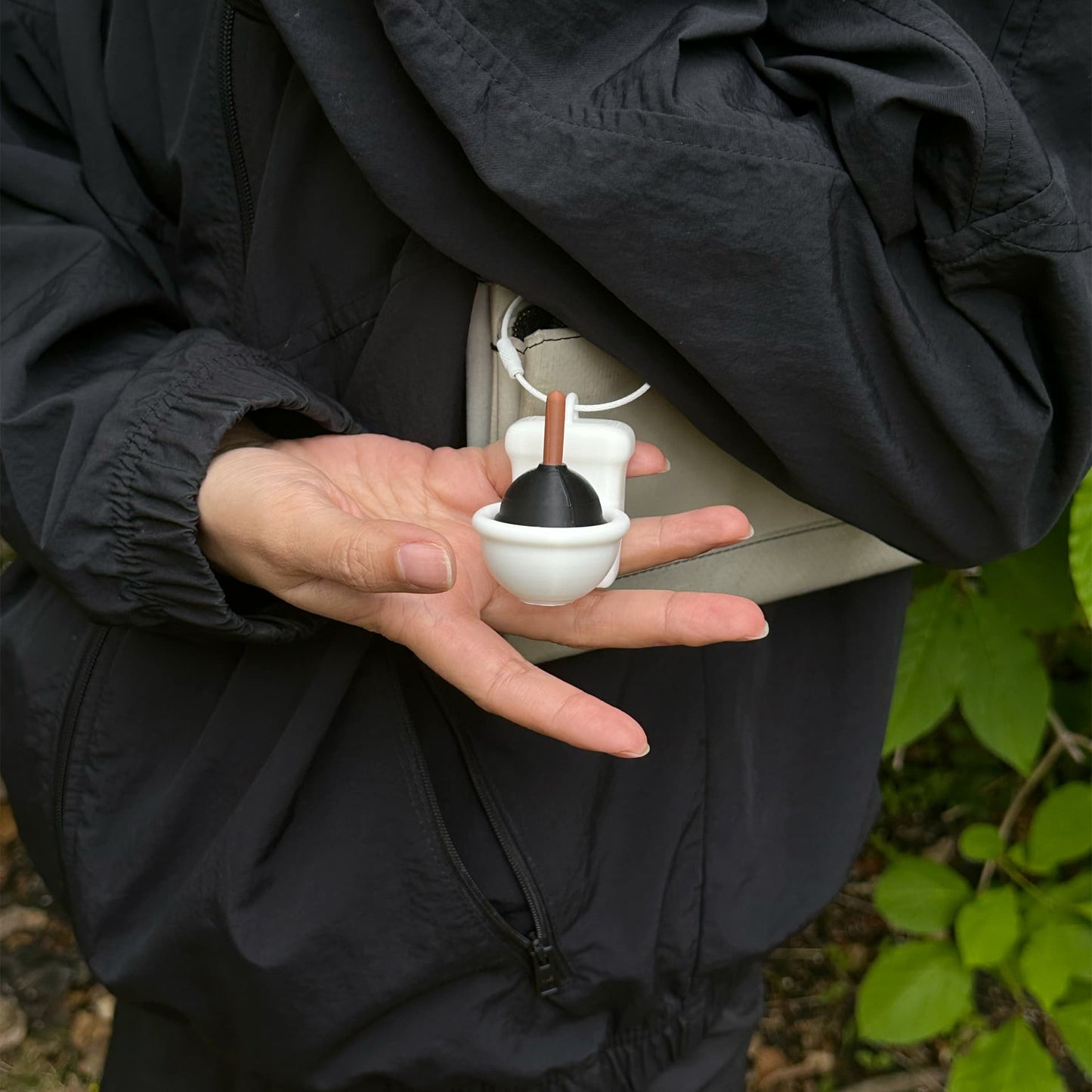 Close-up of Stucky Toilet clipped to a white crossbody bag