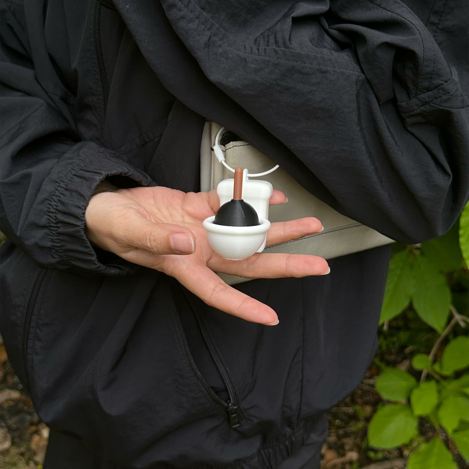 Close-up of Stucky Toilet clipped to a white crossbody bag