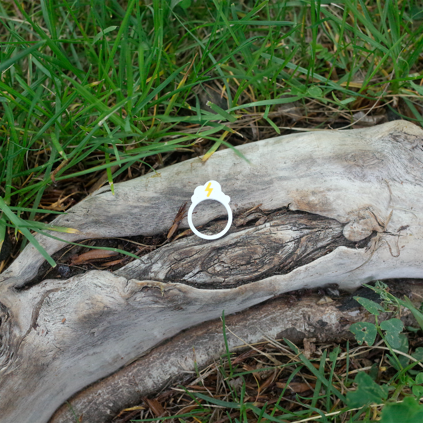 A white ring with a yellow lightning bolt above a cloud, resting on textured wood.