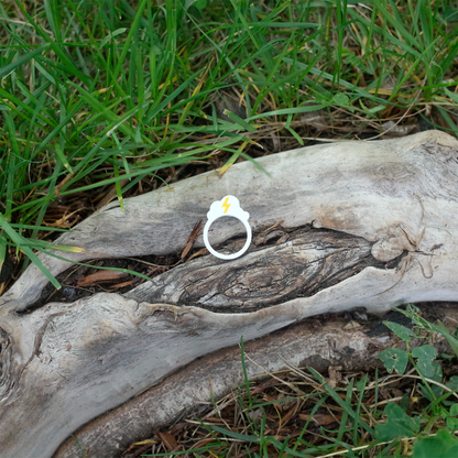 A white ring with a yellow lightning bolt above a cloud, resting on textured wood.